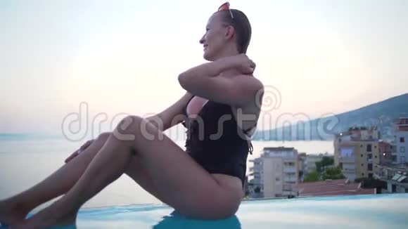 豪华旅行快乐的女人穿比基尼在游泳池的边缘放松年轻女性正在观看美丽的景色视频的预览图