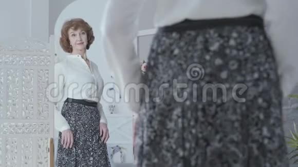 可爱优雅的老女人看着镜子审视着她的倒影那位女士看着她穿着新长裙视频的预览图