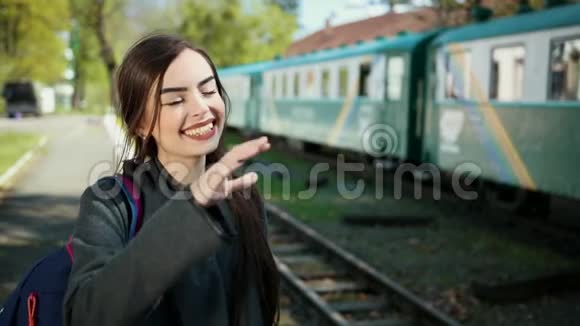 一个美丽而快乐的女孩站在火车车厢前手里拿着一张票向她道别视频的预览图