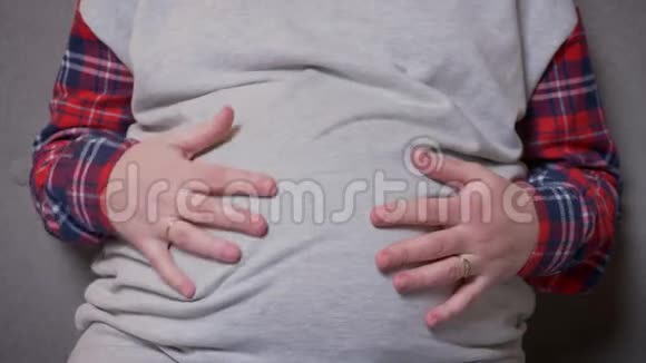 通过摄像机拍摄的特写镜头从孕妇的胃到孕妇的脸看着镜头开心地笑着视频的预览图