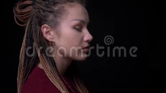 年轻的黑发女孩穿着刺和可怕的镜头转向相机平静地观看它的黑色背景视频的预览图