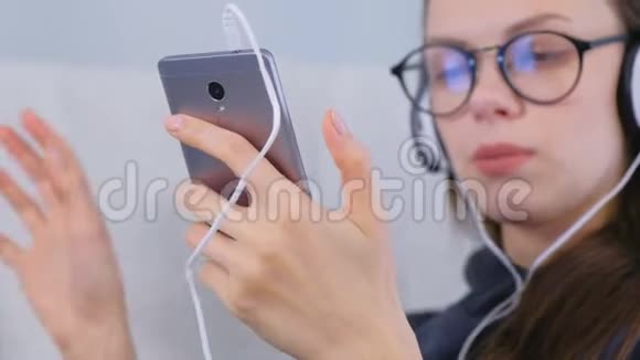 女人用手在智能手机上听音乐视频的预览图