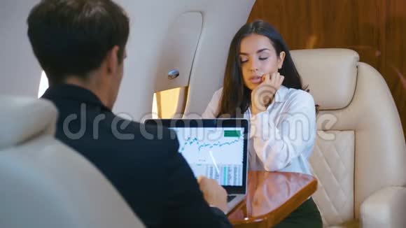 成功的女商人和商人乘坐私人飞机女人在看镜头男人为笔记本工作视频的预览图