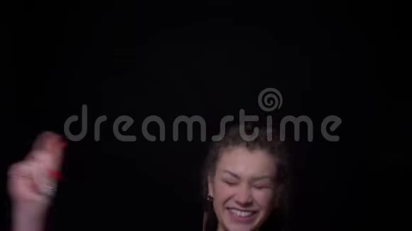 美丽而古怪的黑发女孩穿着刺和可怕的跳跃在极端幸福的黑色背景视频的预览图