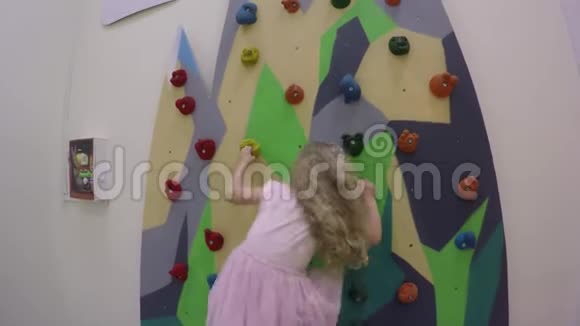 穿着粉色裙子在室内操场攀岩的漂亮女孩视频的预览图