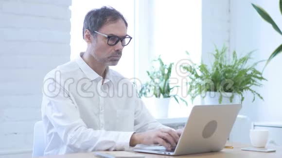 不中年男子在笔记本电脑上工作时摇头拒绝视频的预览图