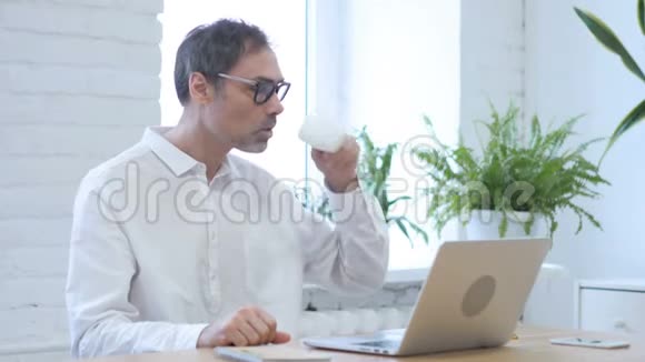 坐在办公室的中年男人一边喝咖啡一边放松视频的预览图