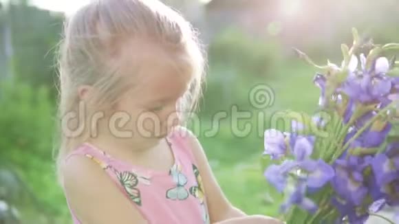 美丽的小女孩带着一束蓝色的铃铛站在花园里视频的预览图