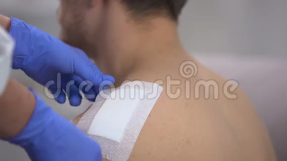 护士双手取下男性患者肩伤处的绷带视频的预览图
