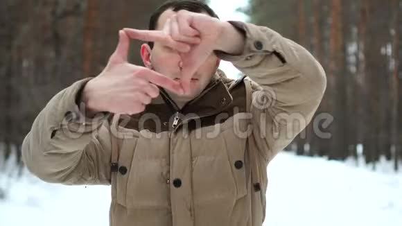 年轻人在冬天森林的背景下做了一个手指架视频的预览图