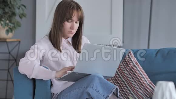 临时坐着的年轻女孩在家做笔记本电脑视频的预览图