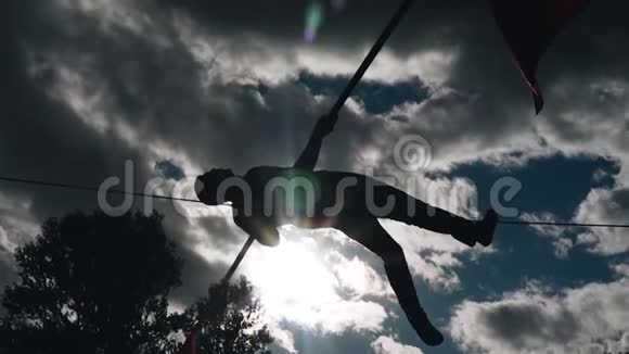 一个坐在绳子上跳过地面的人剪影对着天空不错的镜头视频的预览图