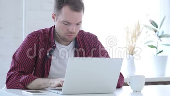 生病的年轻人咳嗽和在笔记本电脑上工作喉咙感染视频的预览图