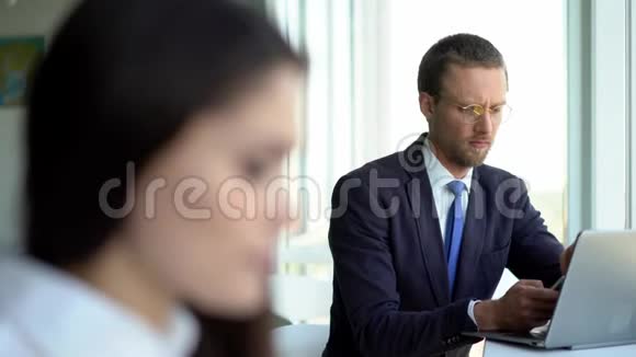 受欢迎的商人正在看着深色的女商人一边在笔记本电脑上工作一边微笑着商务小姐在工作视频的预览图