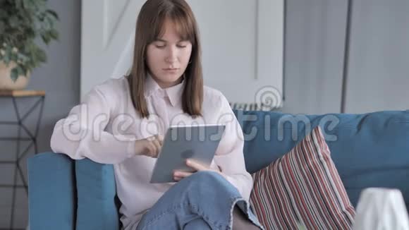 坐在沙发上用平板的休闲女孩视频的预览图