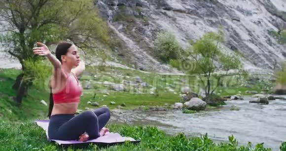 在美丽的夏日里在大自然中一位女士在美丽的河流旁练习瑜伽冥想视频的预览图