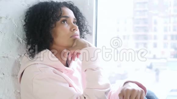年轻的非洲女性思考和头脑风暴坐在窗口视频的预览图