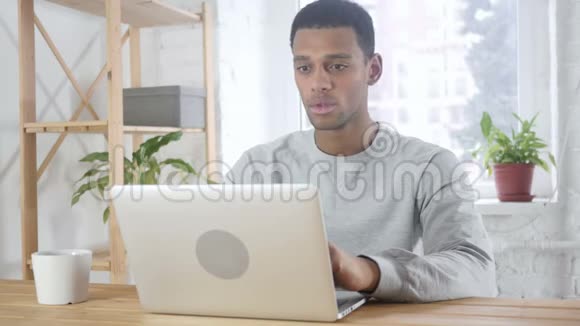 兴奋的美国黑人在笔记本电脑上工作坐在沙发上庆祝成功视频的预览图
