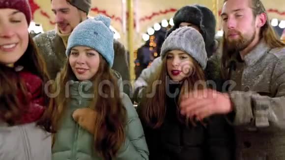 漂亮的女人在新年冬展游乐园的智能手机相机上自拍微笑的朋友很开心视频的预览图