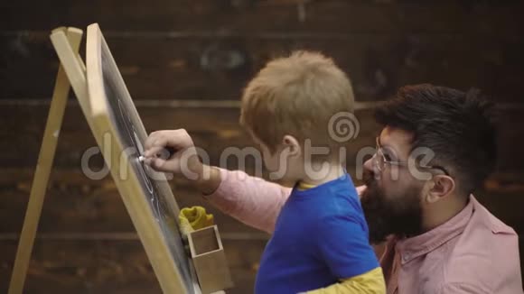 小男孩在黑板上用粉笔画画幼儿教育和游戏观念棋盘学习视频的预览图