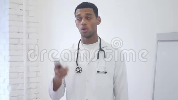 站在医院里的非裔美国人医生在用手机说话视频的预览图