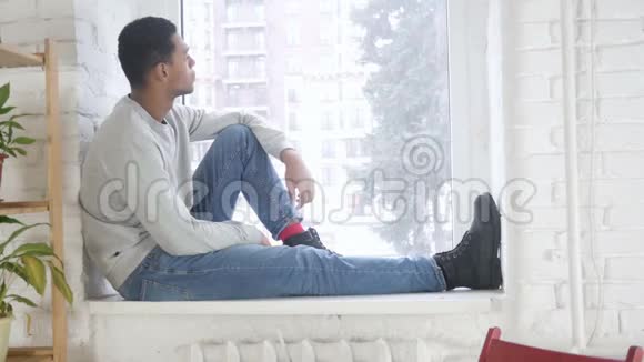 坐在窗口向外看的美国黑人男子视频的预览图