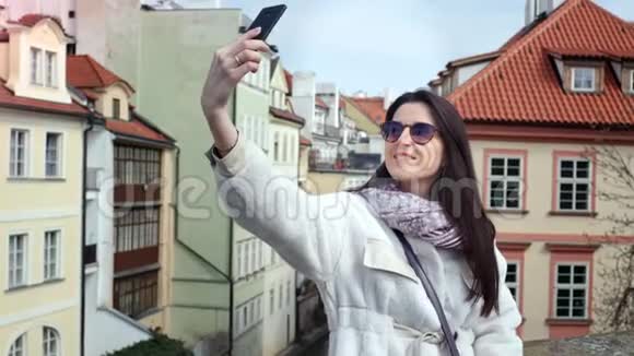 迷人的微笑旅游女性使用智能手机自拍周围是城市街道建筑视频的预览图