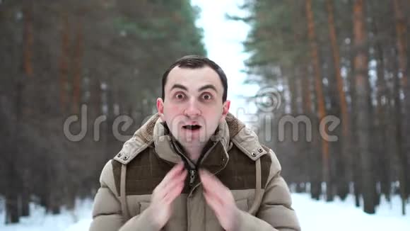 穿着夹克的惊讶男子的肖像在镜头中表现出惊人的情感人站在冬林中视频的预览图