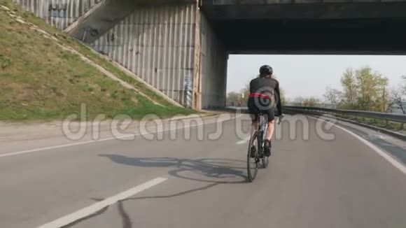 年轻健康的骑自行车的人骑在桥下自行车训练比赛男性骑自行车的人穿着黑色的衣服和头盔慢一点视频的预览图