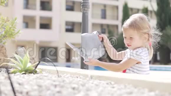 一个金发小女孩轻轻地在街上浇花视频的预览图
