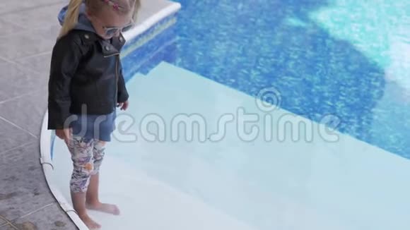 穿着皮夹克的小女孩在游泳池里着脚视频的预览图