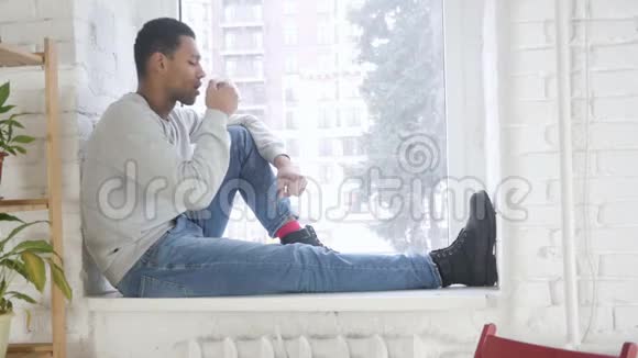 坐在窗边喝咖啡的非裔美国人视频的预览图