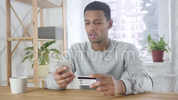 兴奋的美国黑人男子在线购物智能手机付款视频的预览图