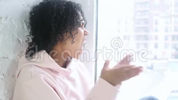 年轻的非洲女人尖叫着疯狂地坐在窗前视频的预览图