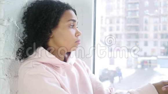 伤心难过的年轻美国黑人妇女坐在窗前视频的预览图