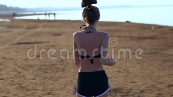 年轻的晒太阳的女人在海滩上奔跑视频的预览图