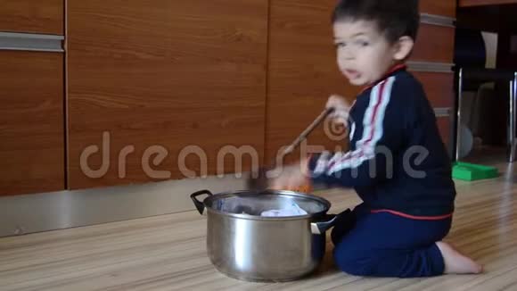可爱的两岁男孩假装用婴儿衣服和纸煮汤视频的预览图