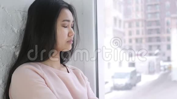 请安静年轻的亚洲女人手指在嘴唇上坐在窗前视频的预览图