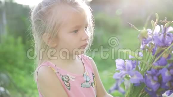 美丽的小女孩带着一束蓝色的铃铛站在花园里视频的预览图