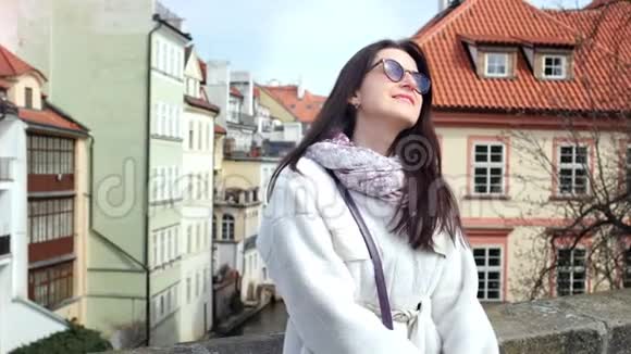 在欧洲城市街头背景的阳台上戴着太阳镜的微笑时尚女孩视频的预览图