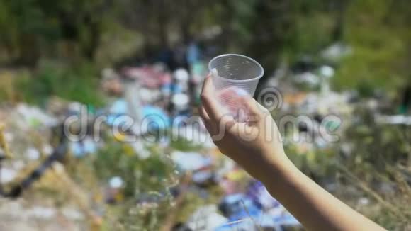 女人把一次性帽子扔到森林中央的露天垃圾场生态视频的预览图