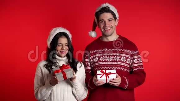 年轻的欧洲夫妇带着圣诞礼物盒微笑着与红色隔离视频的预览图