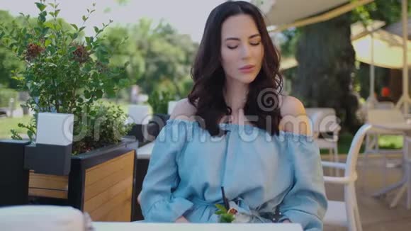 美丽的女人坐在户外餐厅在夏天炎热的日子里喝着莫吉托酒视频的预览图