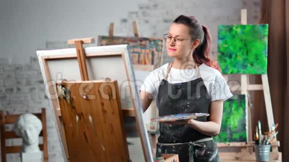 快乐的嬉皮士创意女画家在艺术工作室中画油画视频的预览图