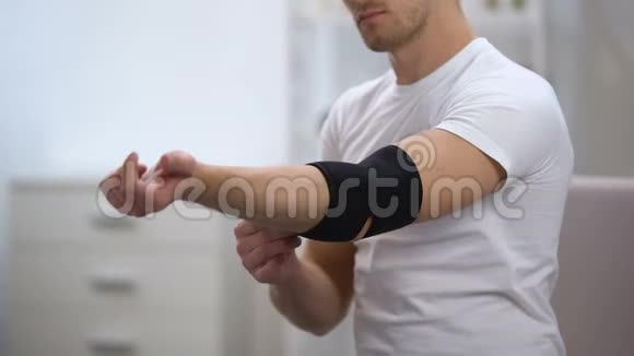 年轻男性应用肘垫矫形器试图移动手骨科视频的预览图