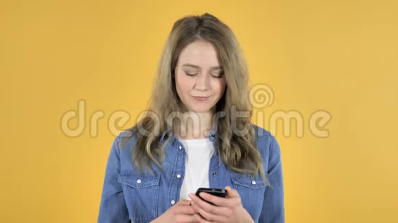 黄色背景下讲智能手机的少女视频的预览图