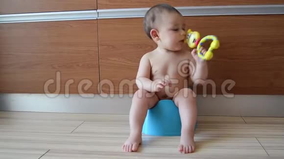 可爱的六个月大的男婴坐在马桶上玩玩具视频的预览图