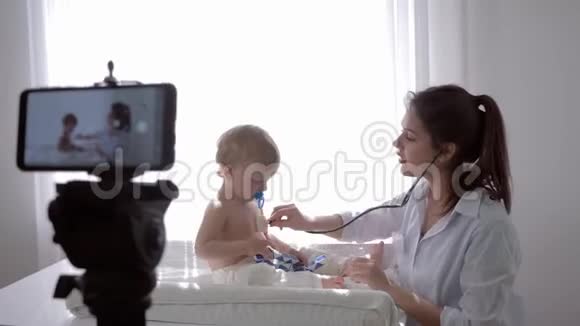 电子学习女医生用听诊器检查病人男孩的心跳和呼吸在记录视频的预览图