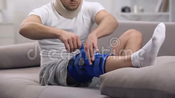 男带泡沫塑料颈圈固定氯丁橡胶护膝躺在沙发上康复中心视频的预览图