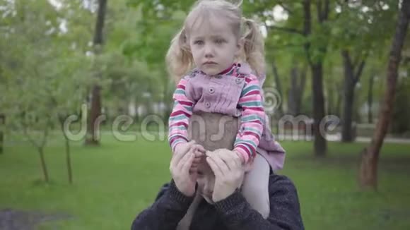 英俊的金发男孩和她可爱的妹妹在公园里玩把她抱在肩膀上那个男孩想振作起来视频的预览图